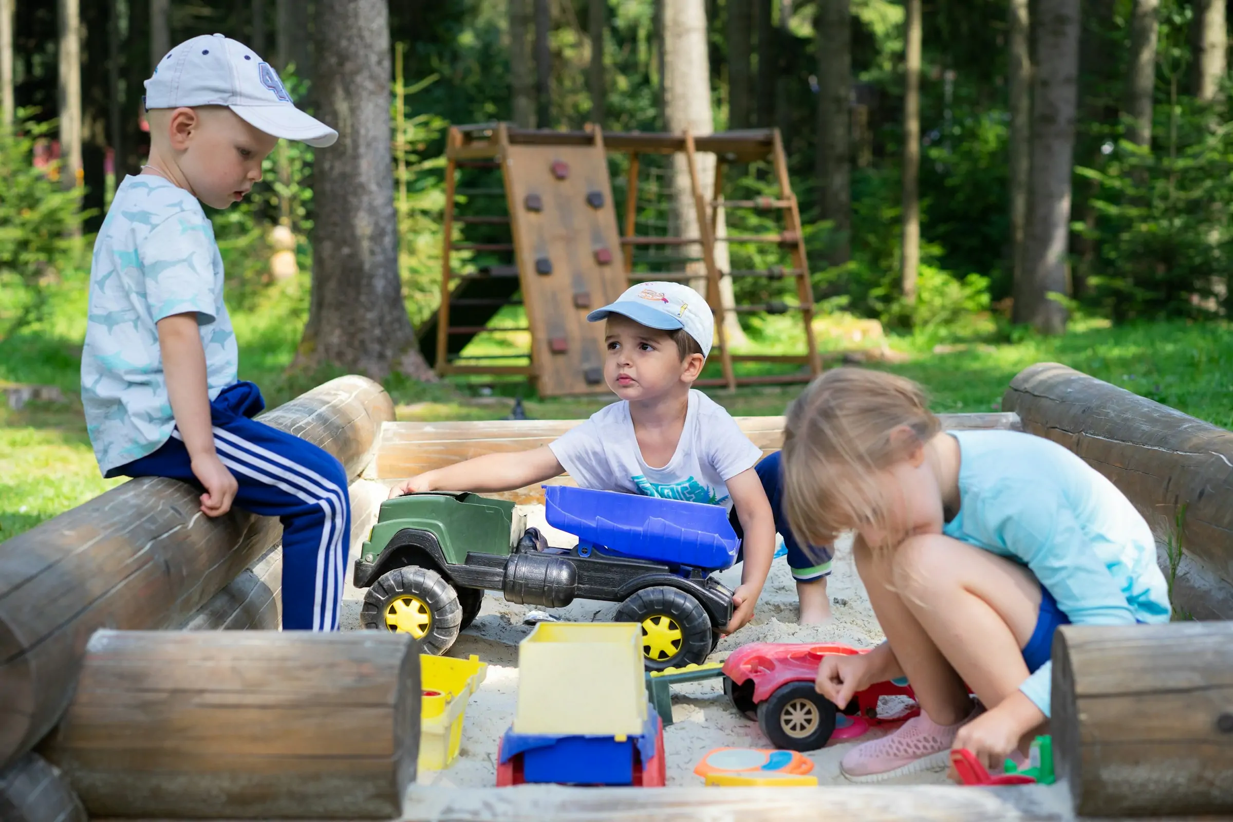 kids playing outdoors in sand with several outdoor toys.