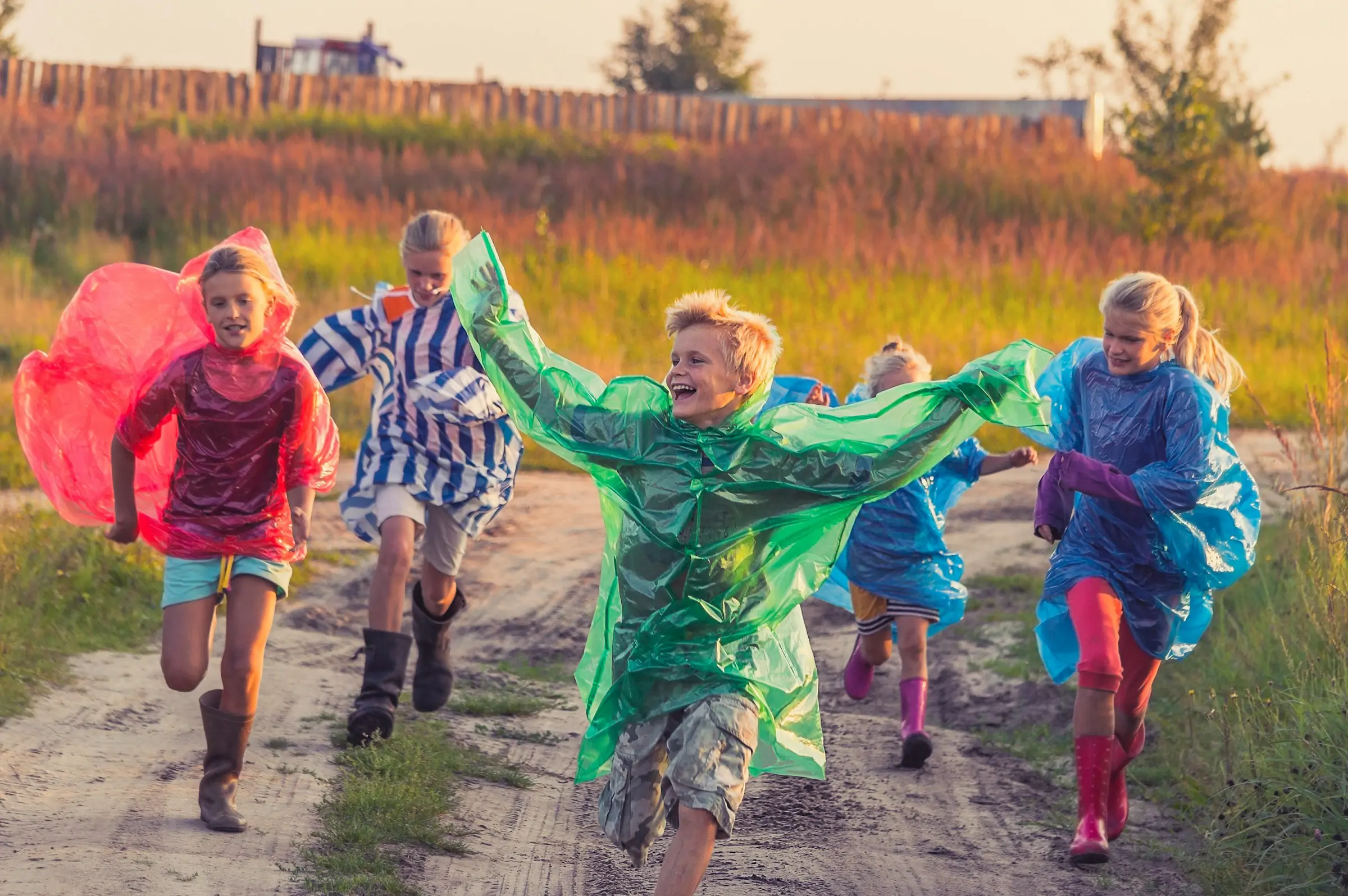 Kids running with raincoats on.