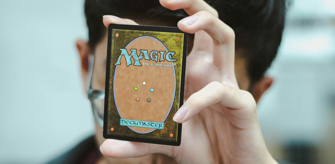 Boy holding up a Magic The Gathering trading card showing the back
