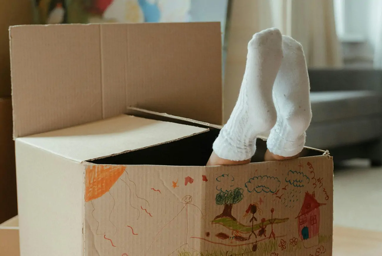 Child inside a cradboard box with drawings on the outside