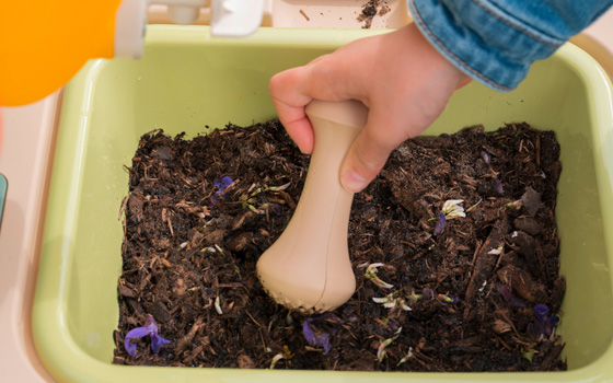 Close up of a child playing with a mud kitchen