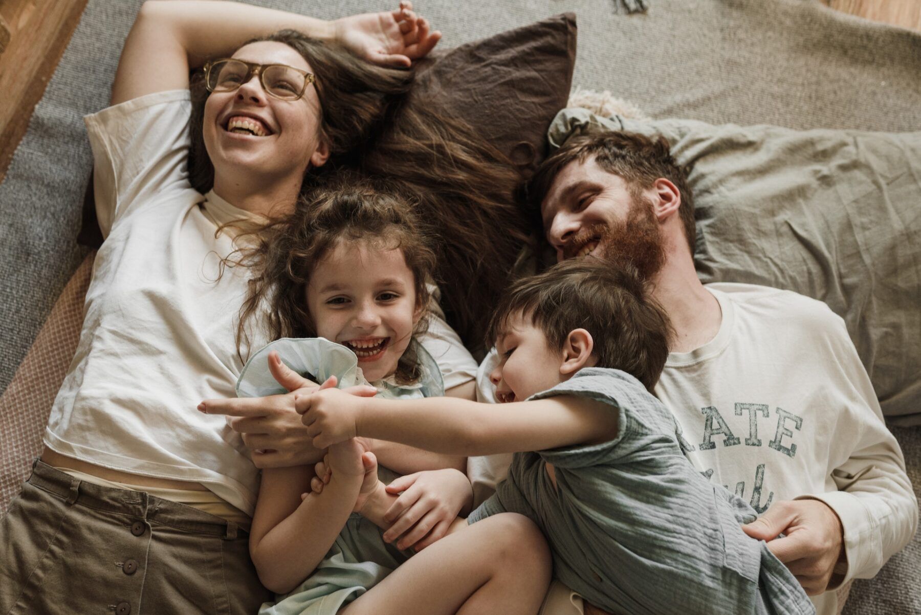 Family laughing in bed.