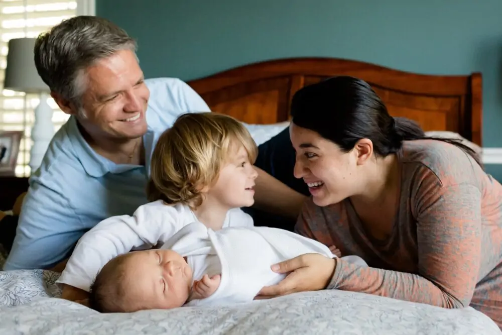 Family sitting on bed and smiling.