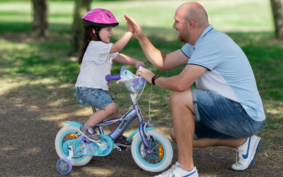 Father and daughter riding a bike with stabilizers