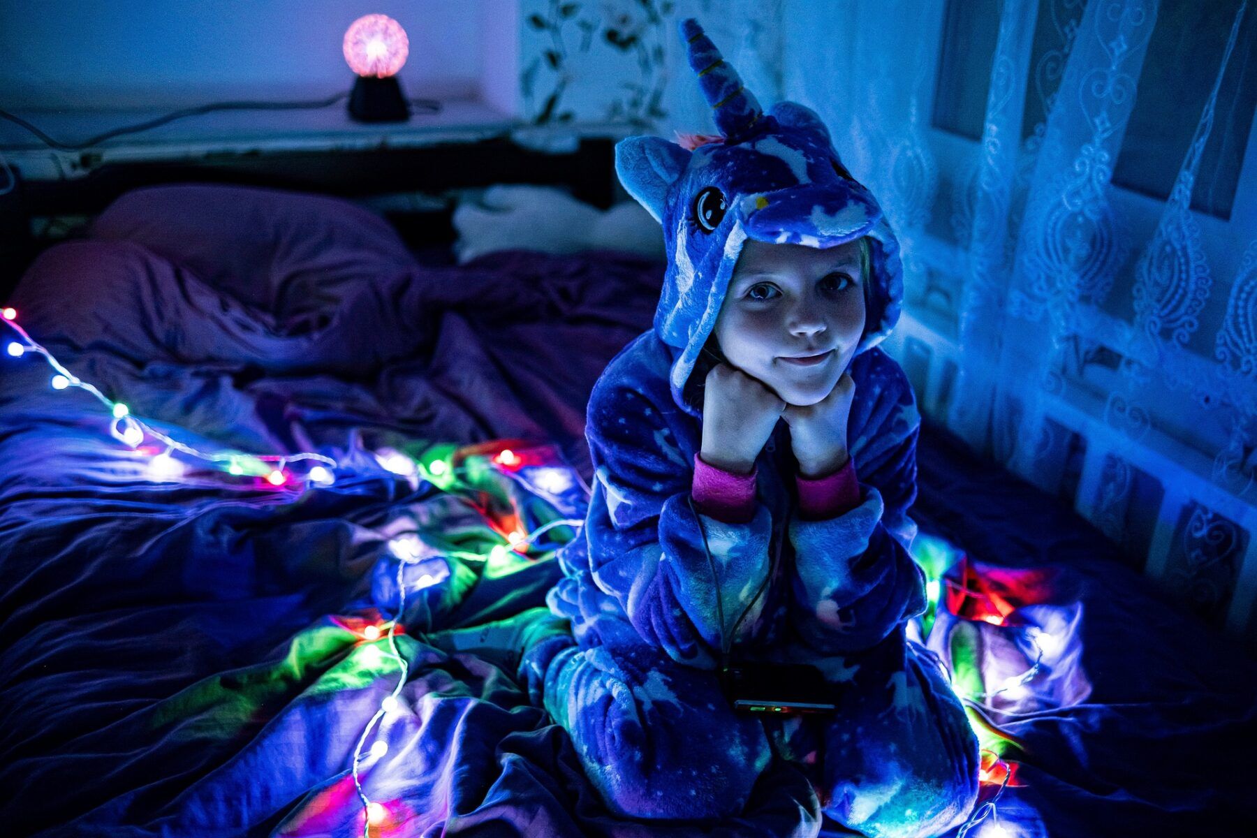 Girl sits on bed surrounded by night lights.