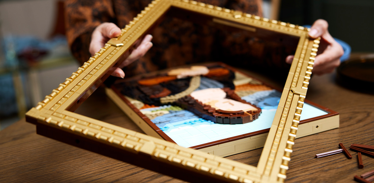 Person placing a LEGO frame on a work of art or photograph