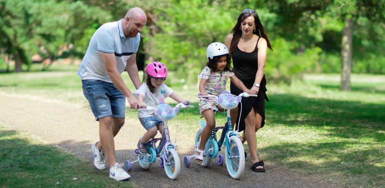 Parents pushing their children on their bikes