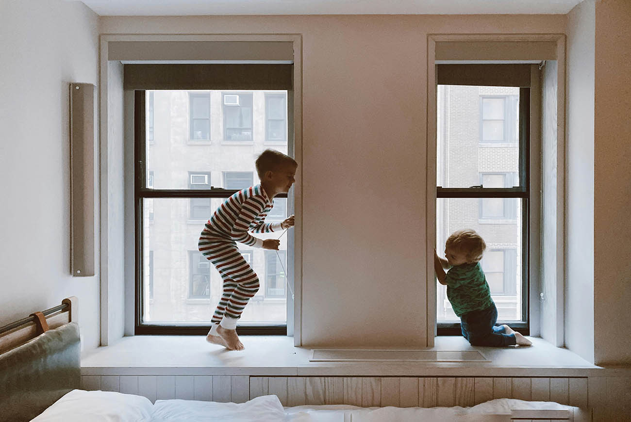 Two children jumping in front of a window