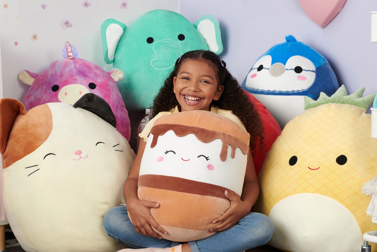 Child surrounded by Squishmallows,