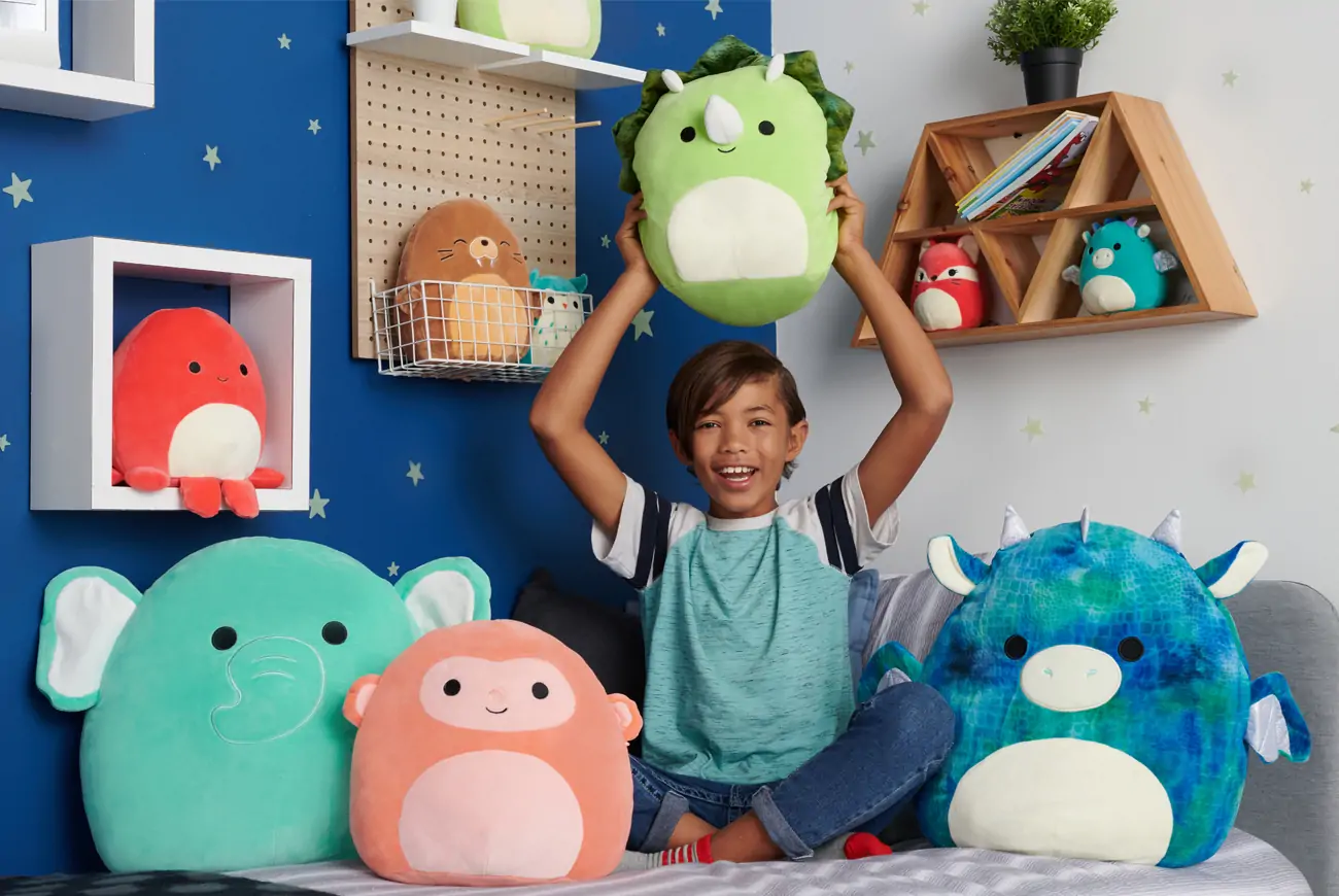 Kid holds up squishmallows.