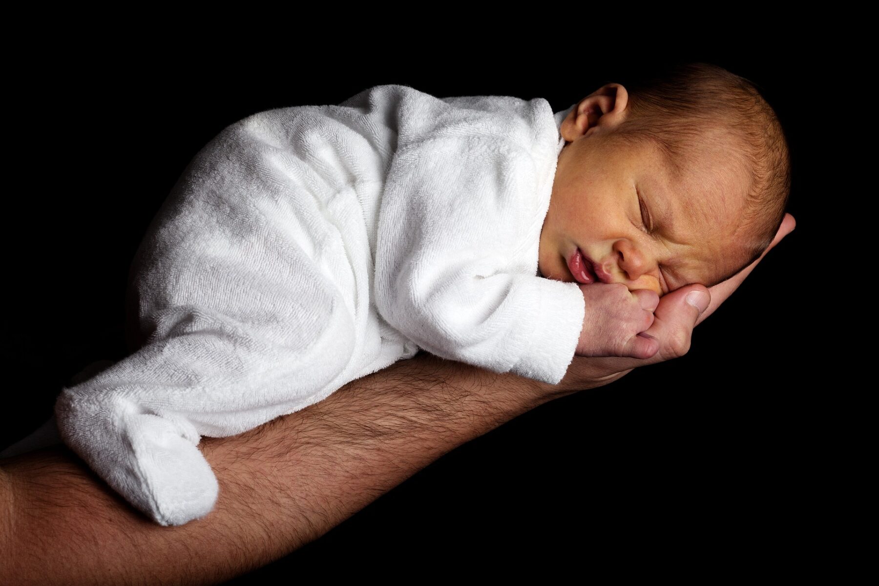 A baby asleep in someone's arms.