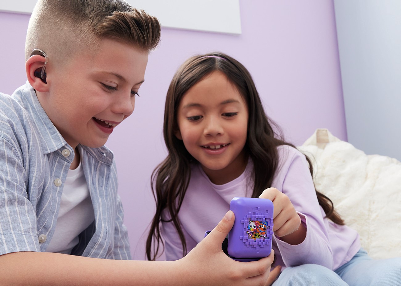 Two kids play with Bitzee toy.