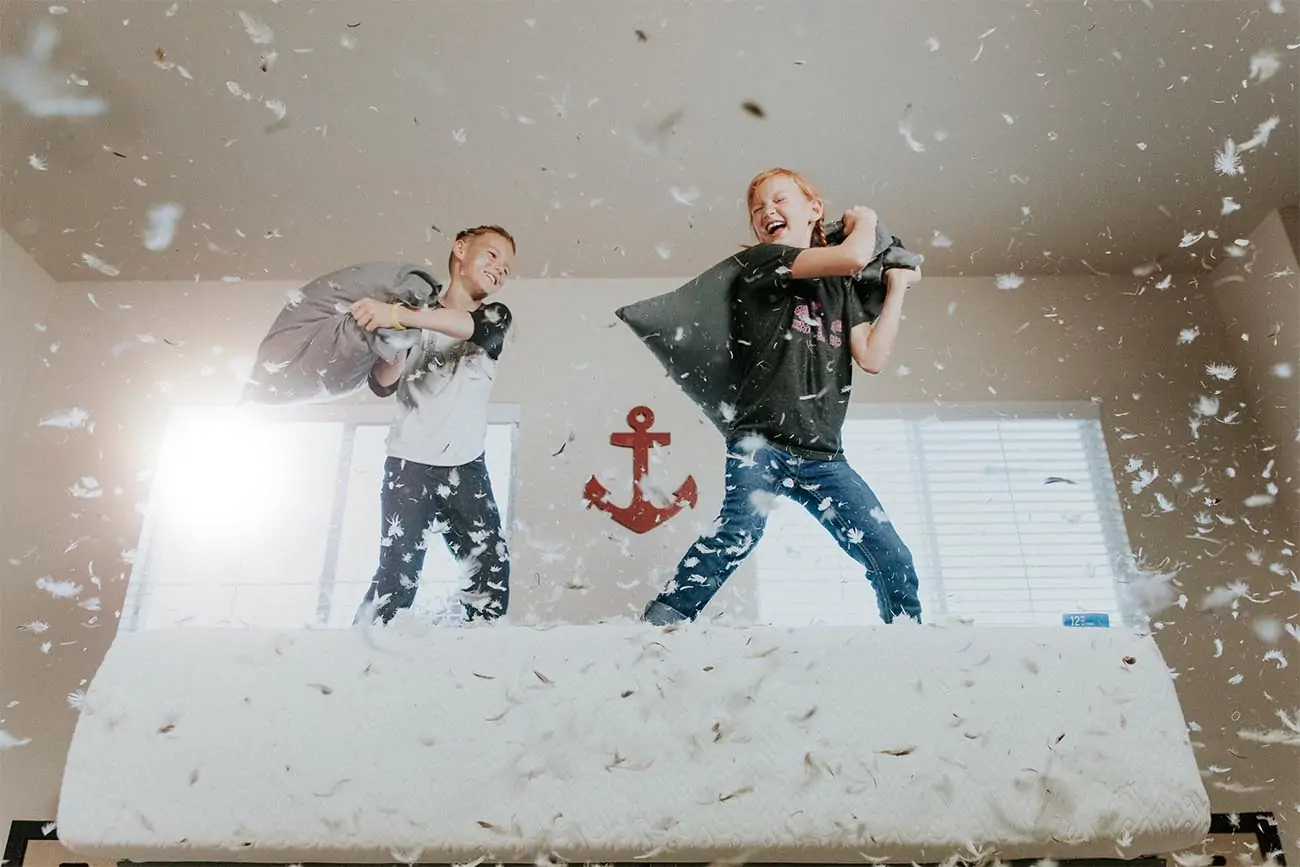 two children having a pillow fight on a bed