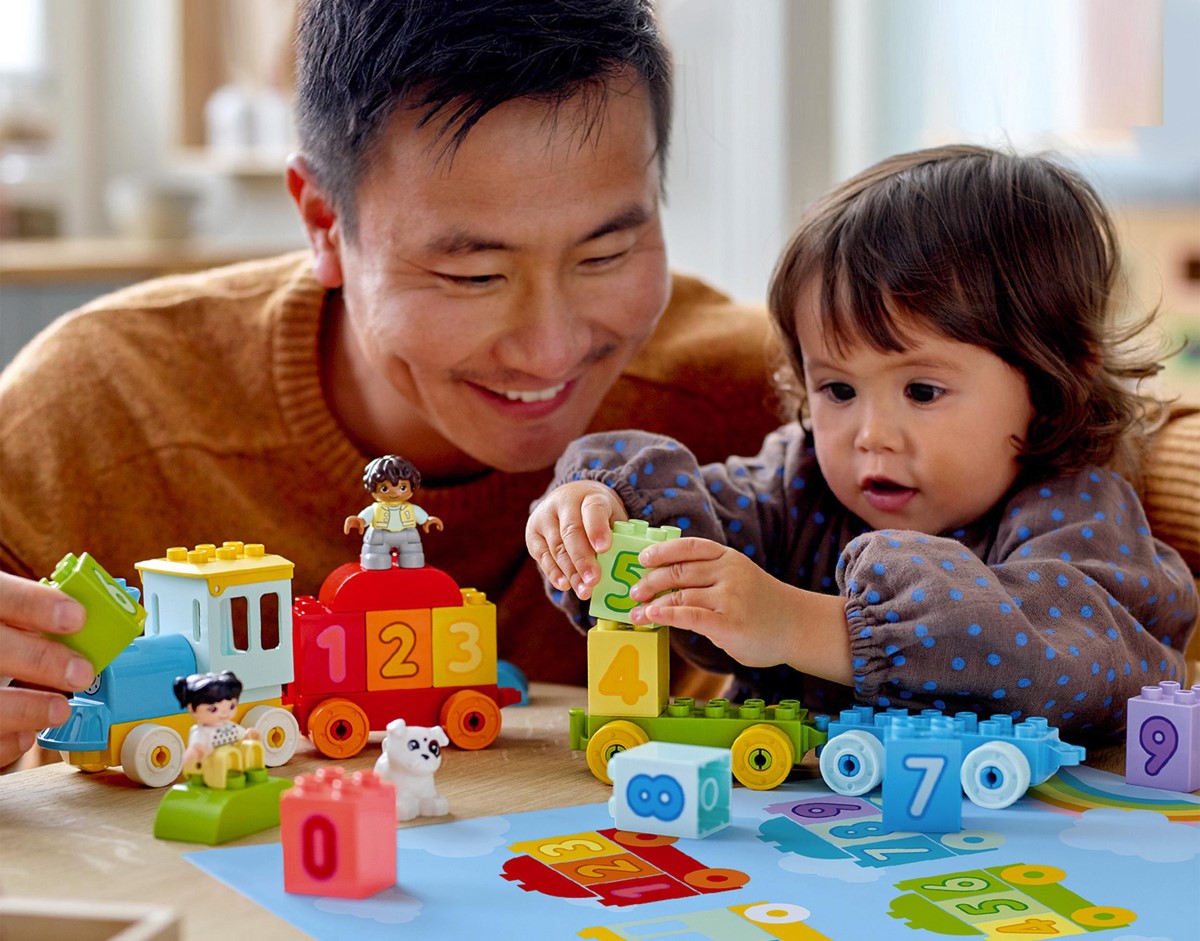 Dad and daughter play with lego.