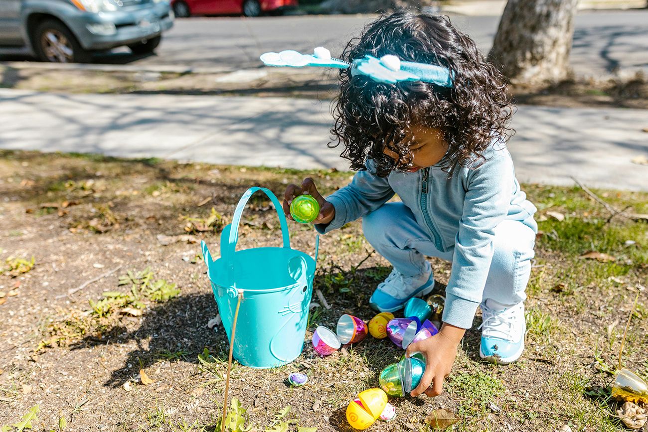 a child on an easter egg hunt, with her basket picking up eggs