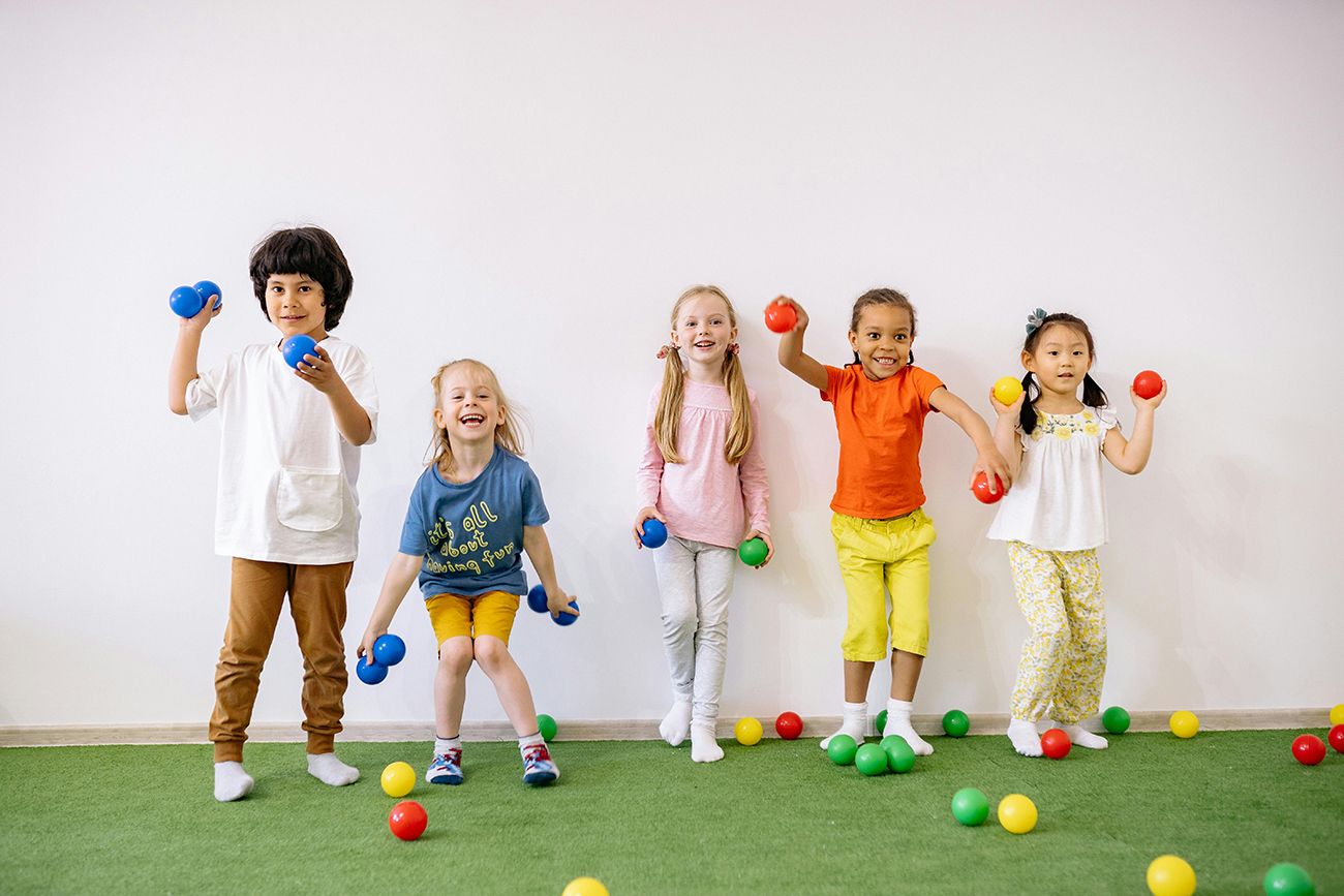 a group of children standing in a line ready to throw colourful balls