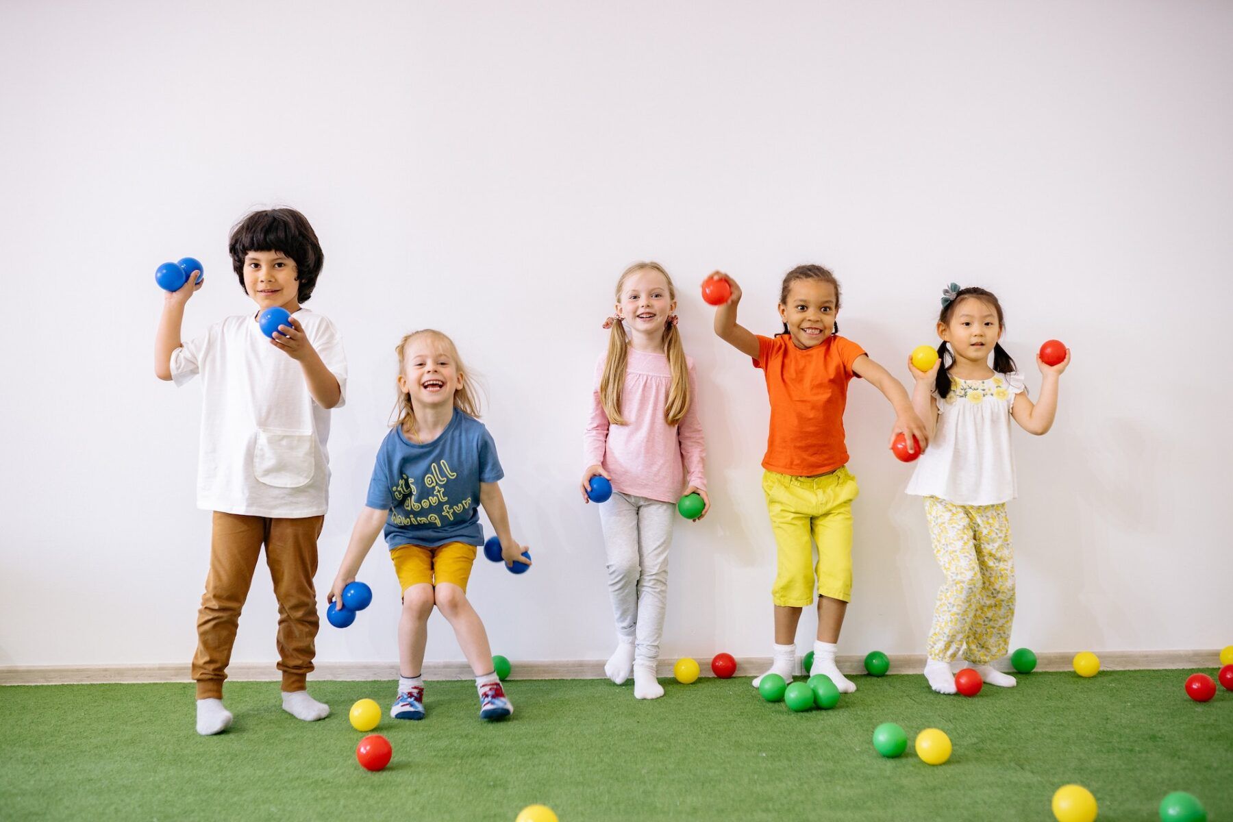 a group of children all in a line laughing with different coloured balls