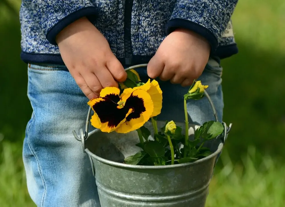 child holds gardening pot.