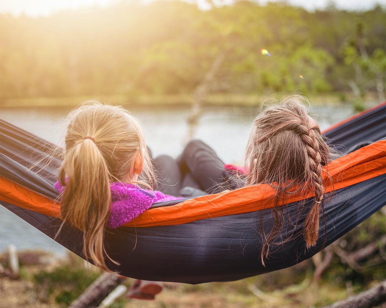 two girls lying in a hammock outside watching the sun