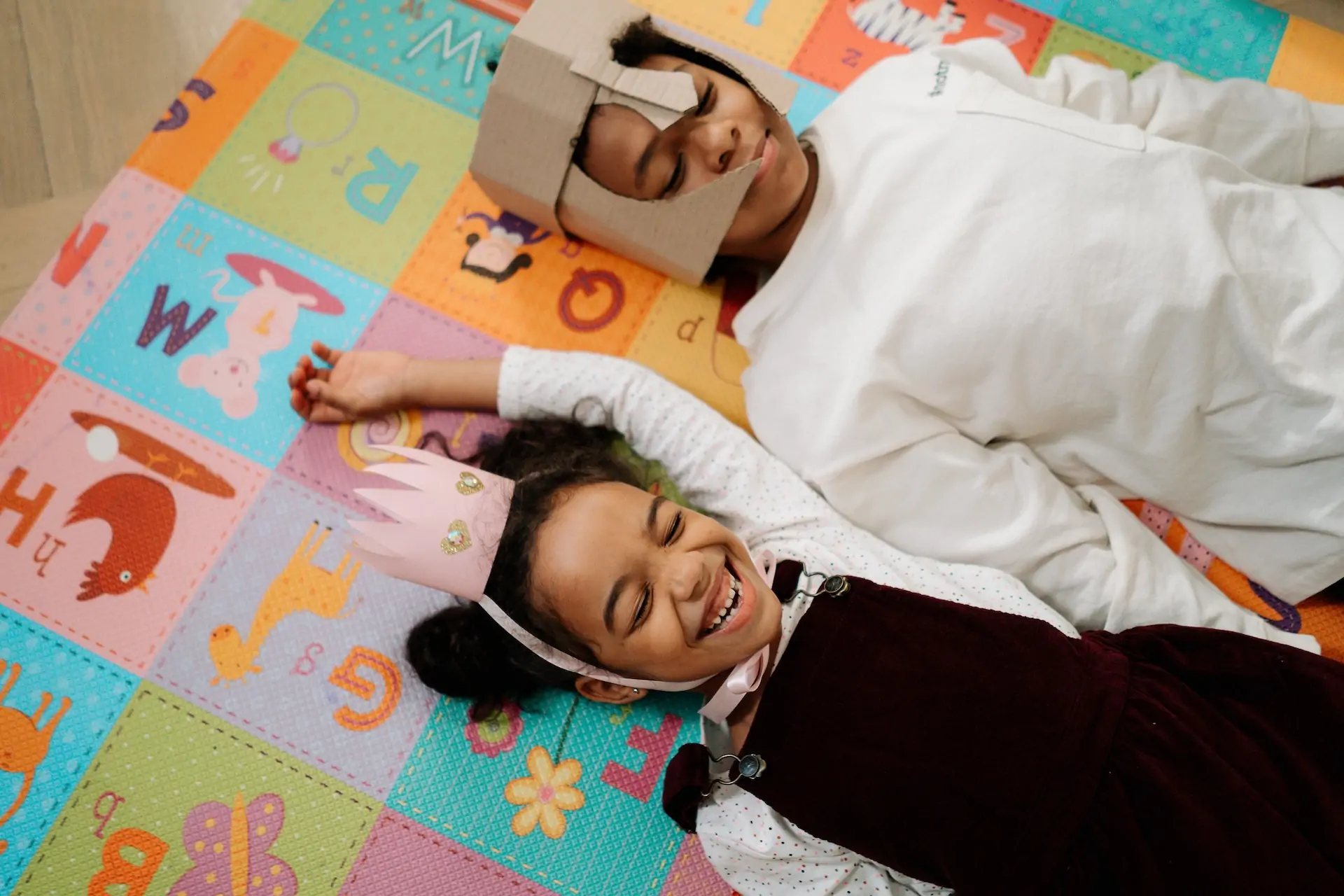 Two kids play on a mat together