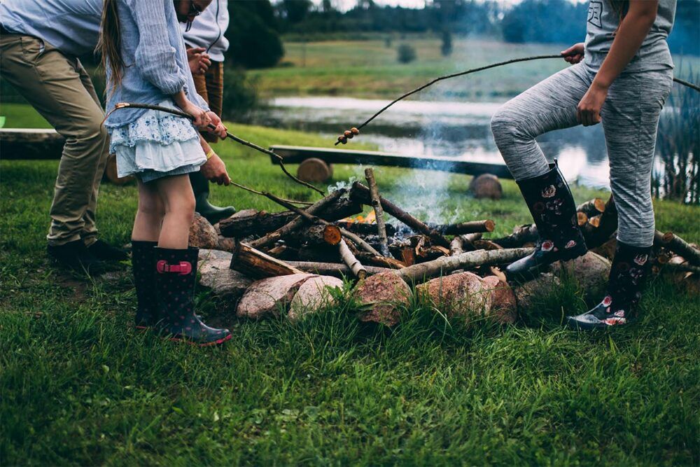 children toasting marshmallows around a campfire in wellies