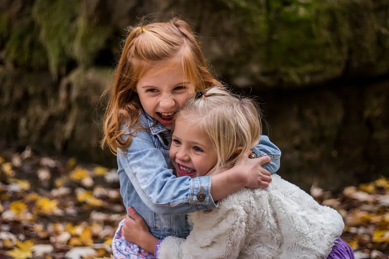 Two little girls hugging each other.