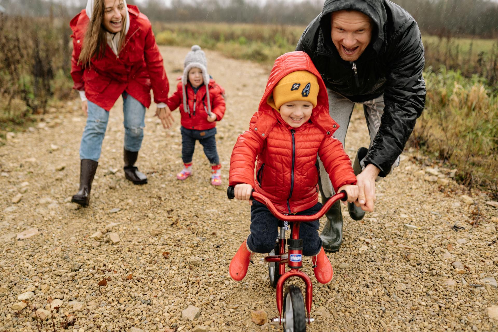 Family teaching kid to ride a bike.