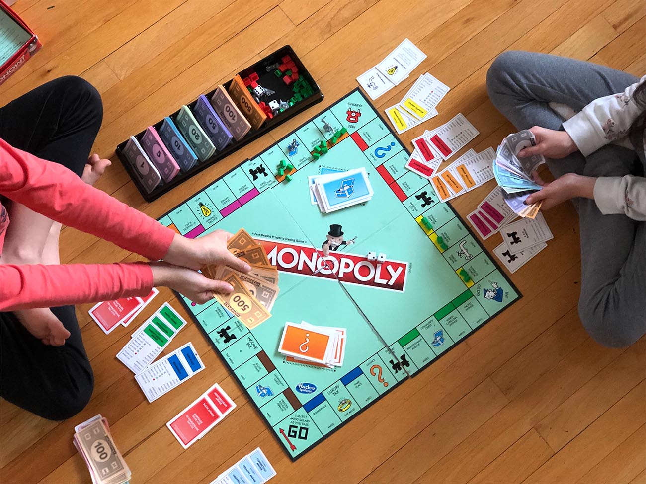 two children playing monopoly on the floor