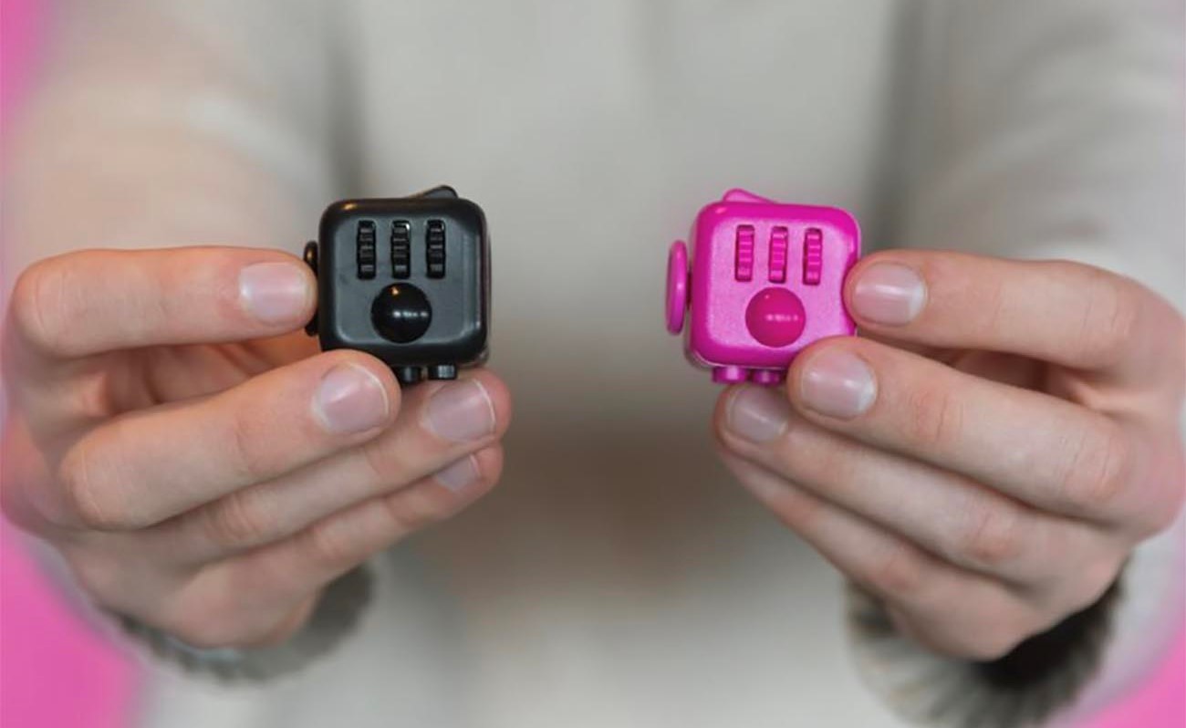 Boy holds two fidget cubes.